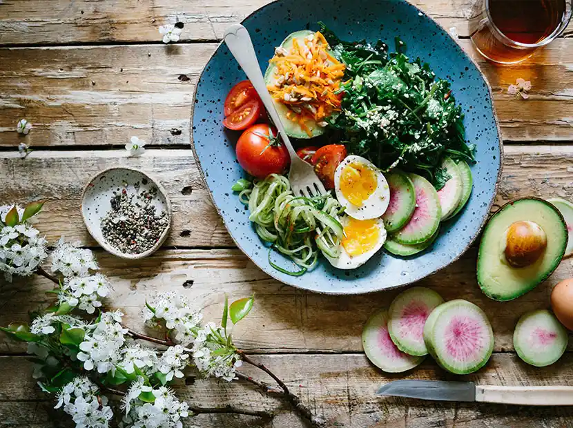 Da Baffo Catering München Salatteller auf Holztisch mit Spinat, Ei, Tomaten, Avocado und Feigen.