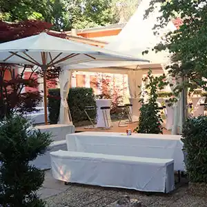 Pavillion mit Sonnemschirm und gedeckten Tischen.