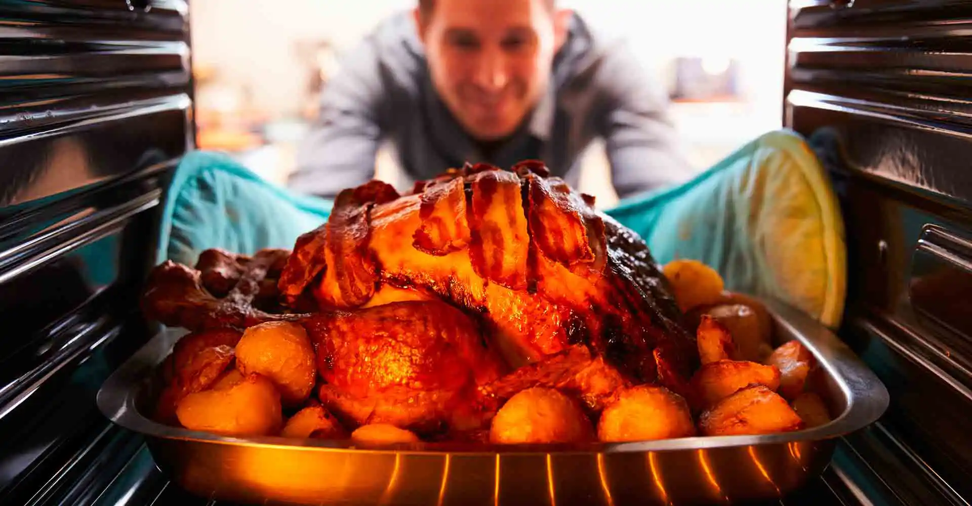 Mann holt Braten aus dem Ofen