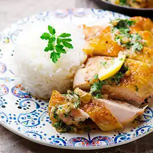 Teller mit Hähnchenbrust und Reis an Zitronensauce.