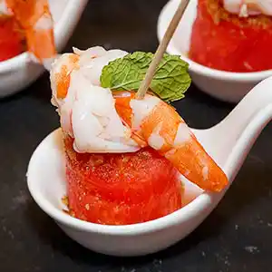 Gebratene Garnelen auf Melonensockel und Minzgarnitur am Spieß.