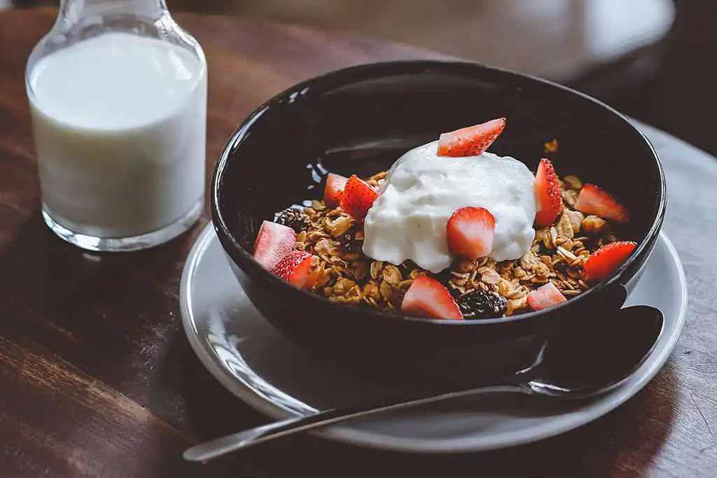 Tisch mit Müsli, Erdbeeren und Yoghurt.