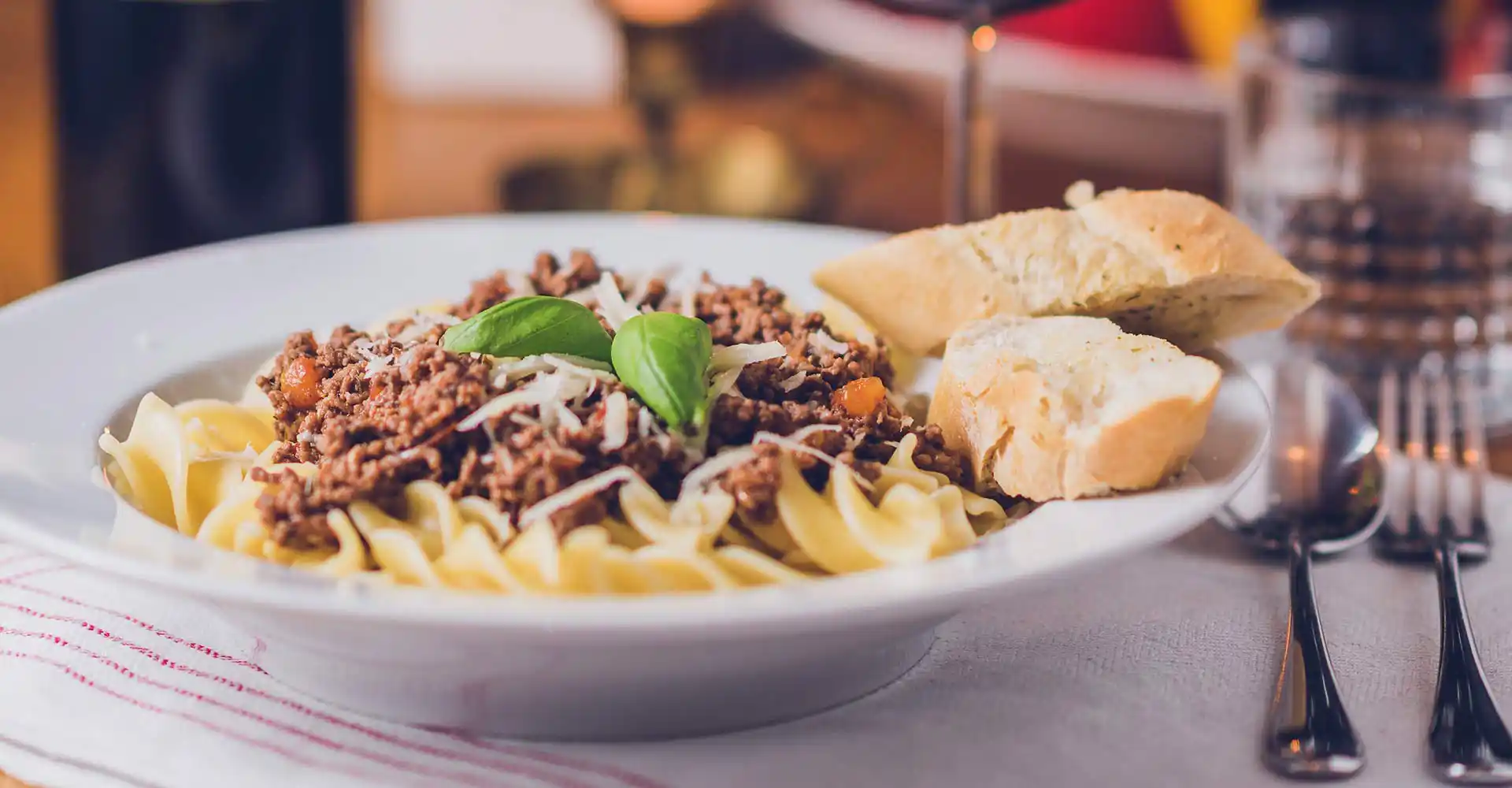 Teller mit Pasta bolognese und Weißbrot.
