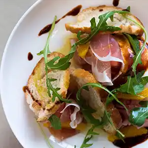 Brotsalatteller mit San Daniela Schinken, Rucola und Oliven.