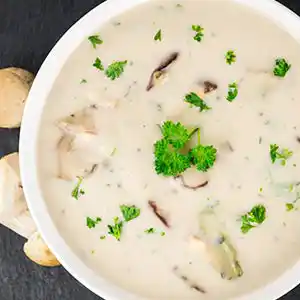 Teller mit Steinpilzsuppe und Petersilie.