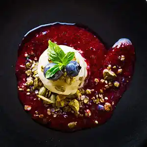 Selbstgemachtes Vanilleeis auf heißen Beeren und Nussgarnitur.